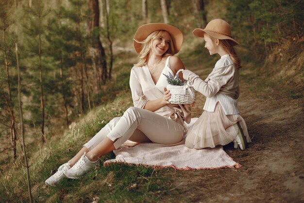 Elegante madre con hija en un bosque de verano