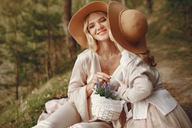 Elegante madre con hija en un bosque de verano