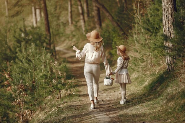 Elegante madre con hija en un bosque de verano