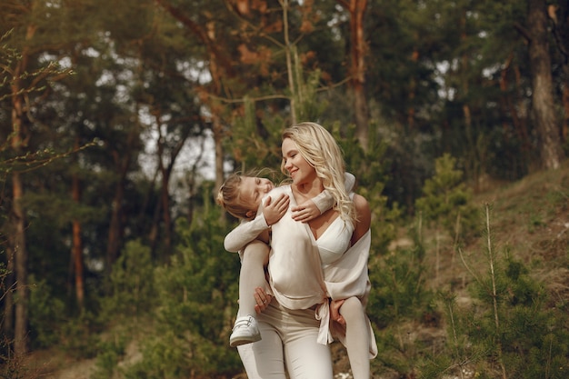 Elegante madre con hija en un bosque de verano