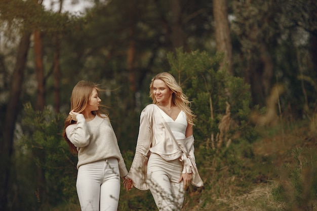 Elegante madre con hija en un bosque de verano