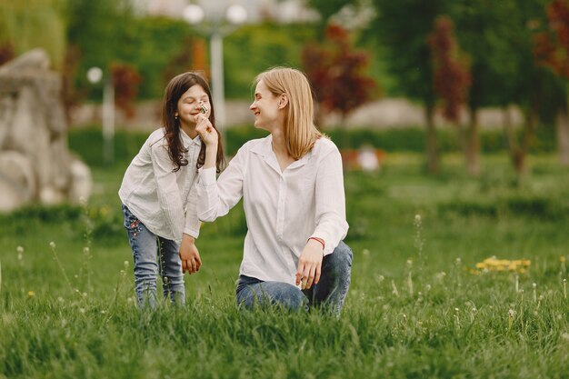 Elegante madre con hija en un bosque de verano