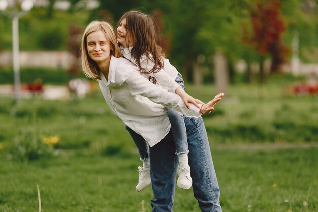 Elegante madre con hija en un bosque de verano