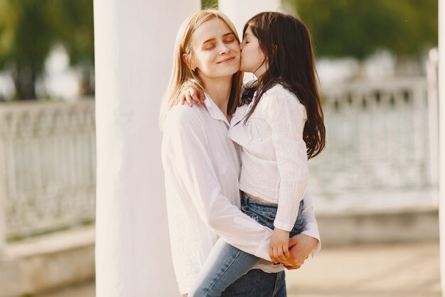 Elegante madre con hija en un bosque de verano