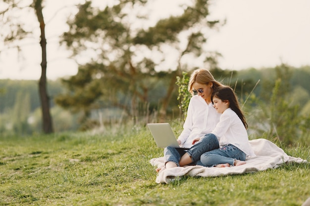 Elegante madre con hija en un bosque de verano