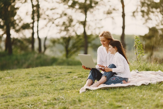 Elegante madre con hija en un bosque de verano