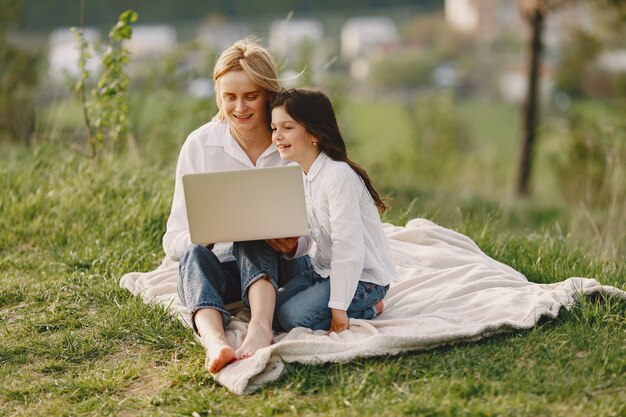 Elegante madre con hija en un bosque de verano