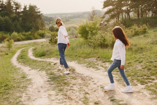 Elegante madre con hija en un bosque de verano