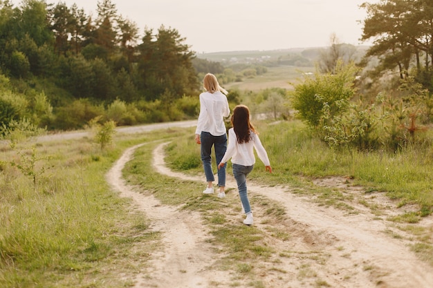 Elegante madre con hija en un bosque de verano