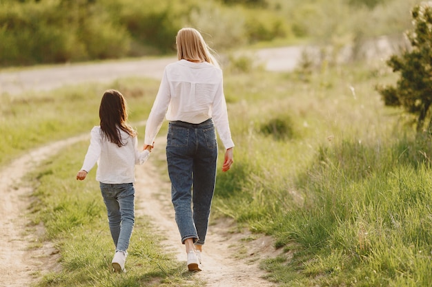 Elegante madre con hija en un bosque de verano