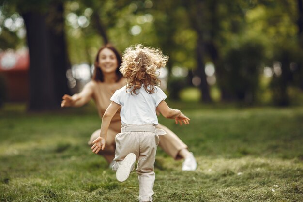 Elegante madre con hija en un bosque de verano