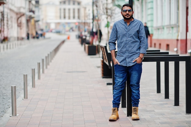 Elegante modelo de barba india con ropa informal posada al aire libre en la calle de la India