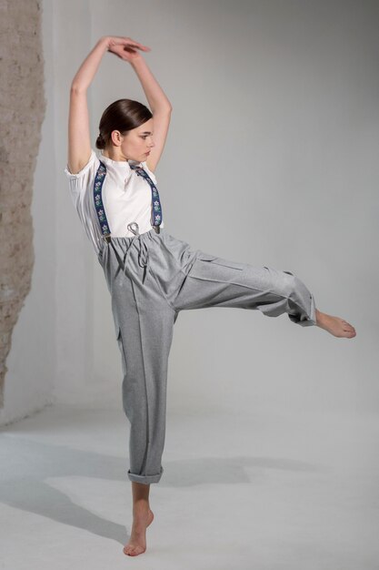 Elegante modelo de mujer bailando en el estudio con elegante camisa blanca y tirantes. nuevo concepto de feminidad