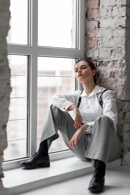 Elegante modelo de mujer posando en una ventana en elegante camisa blanca y tirantes. nuevo concepto de feminidad