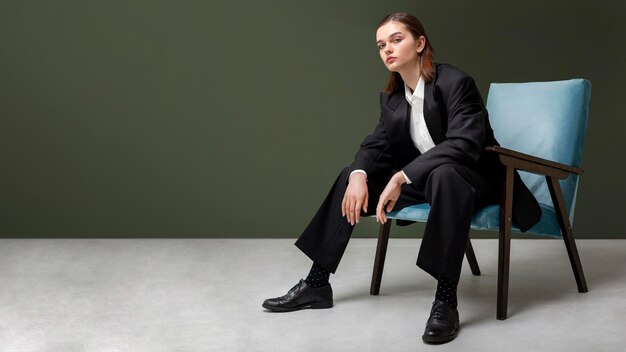 Elegante modelo de mujer sentada en un sillón con un traje de chaqueta. nuevo concepto de feminidad