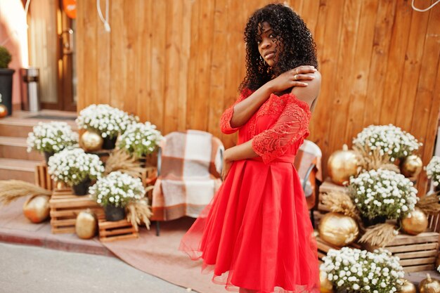 Elegante y moderna mujer afro francia rizada posada en el día de otoño con vestido rojo Modelo femenino africano negro