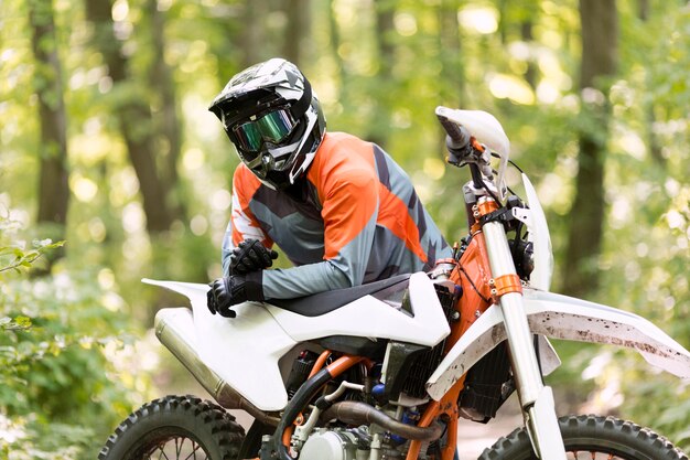 Elegante motociclista posando en el bosque