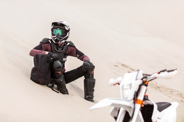 Elegante motociclista relajante en el desierto