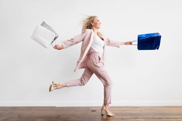 Elegante mujer adulta corriendo con bolsas de compras