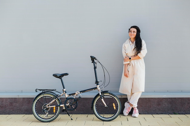 Elegante mujer adulta posando con bicicleta ecológica