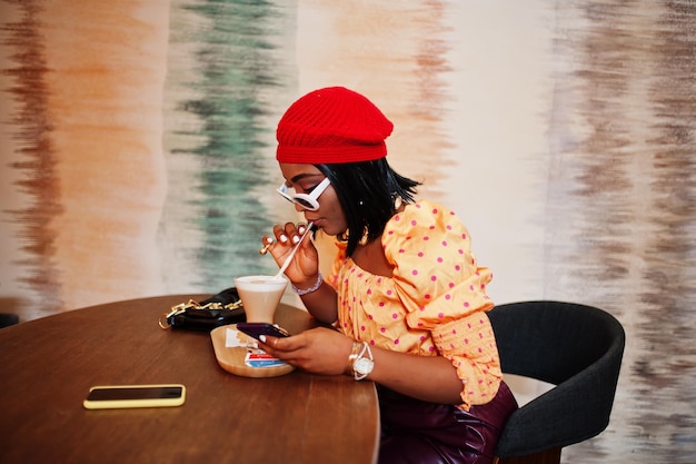 Foto gratuita elegante mujer afroamericana en boina francesa roja blusa de lunares con cadena de cuello dorado pose interior