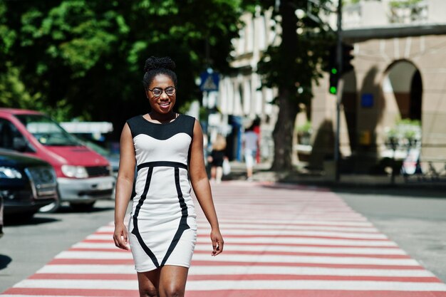Elegante mujer afroamericana caminando en el paso de peatones o en el paso de peatones