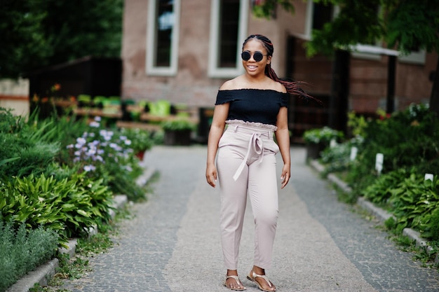 Elegante mujer afroamericana en gafas de sol planteadas al aire libre