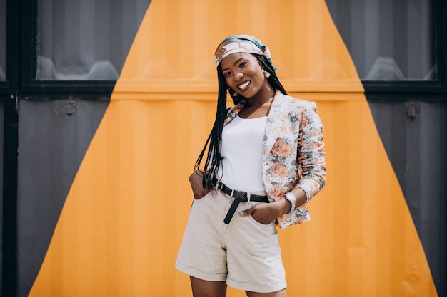 Foto gratuita elegante mujer afroamericana por la pared de color