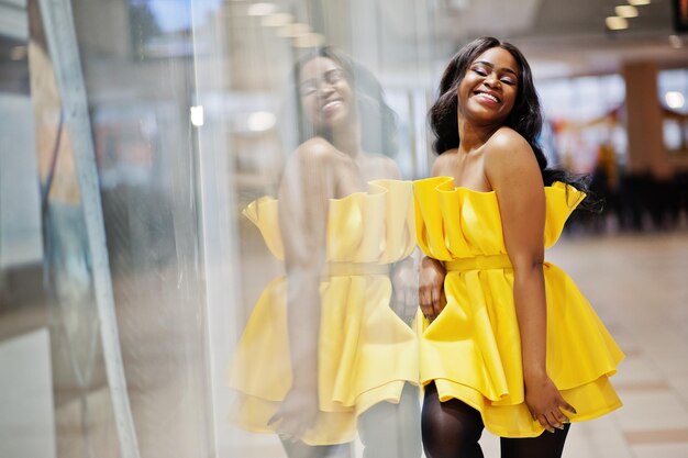 Elegante mujer afroamericana en vestido amarillo posó en el centro comercial