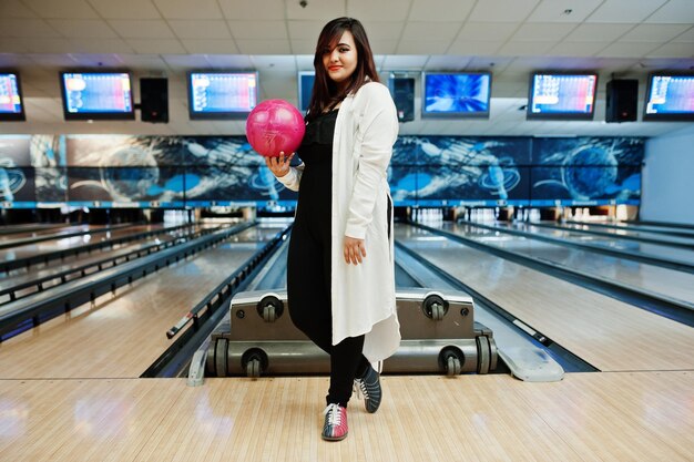 Elegante mujer asiática de pie en la bolera con la pelota en la mano