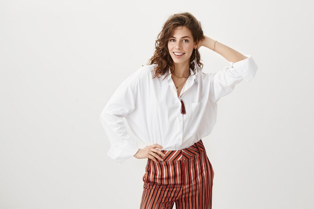 Elegante mujer atractiva mostrar nuevo corte de pelo y sonriendo