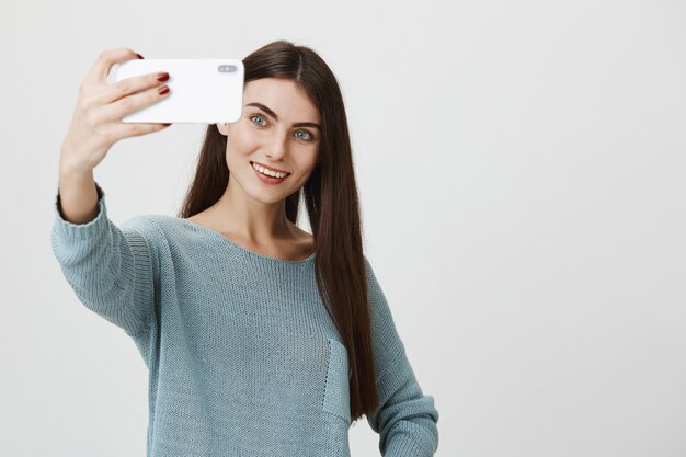 Elegante mujer atractiva sonriendo, tomando selfie