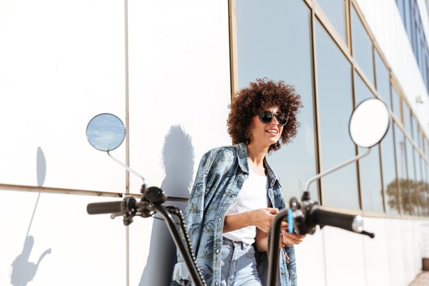 Elegante mujer bonita en gafas de sol mediante teléfono móvil