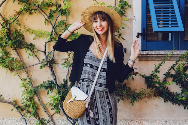 Foto gratuita elegante mujer casual elegante con sombrero de paja y chaqueta negra posando en la calle