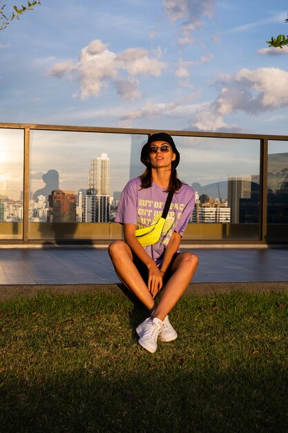 Elegante mujer caucásica en panamá de moda y bolso de neón de cintura en el techo en Bangkok con vista