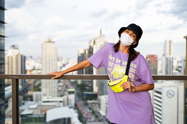 Elegante mujer caucásica en panamá de moda y bolso de neón de cintura en el techo en Bangkok