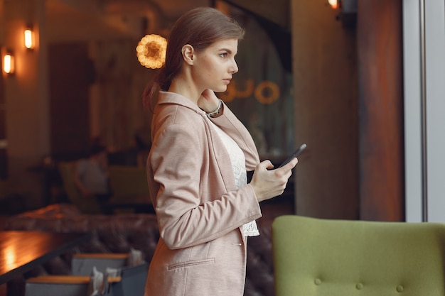 Elegante mujer en una chaqueta rosa pasar tiempo en un café
