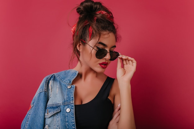 Elegante mujer complacida con labios rojos disfrutando de una sesión de fotos en el espacio claret