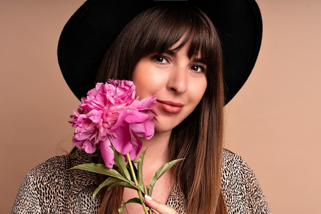 Elegante mujer elegante posando y sosteniendo la flor de peonía. Look glamour romántico.