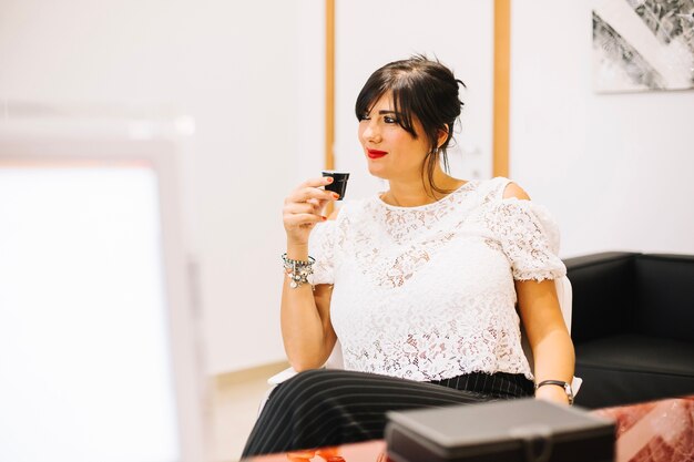 Elegante mujer exitosa disfrutando de café en la oficina