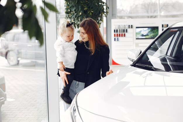 Elegante mujer con hija pequeña en un salón del automóvil