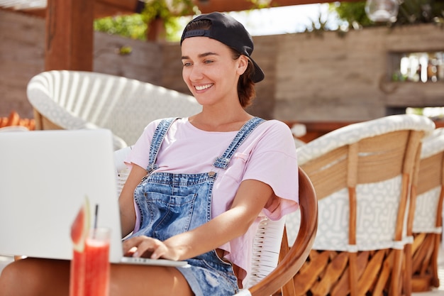 Elegante mujer independiente de ojos azules revisa el correo electrónico en la computadora portátil, utiliza la aplicación en un dispositivo moderno