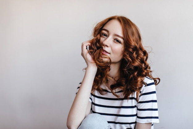 Elegante mujer de jengibre tocando su cabello con una sonrisa. chica europea de ensueño con hermosos ojos.