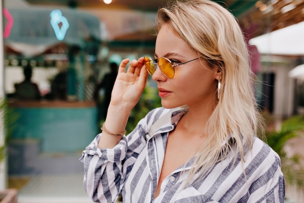 Elegante mujer joven feliz con gafas redondas y camisa despojada