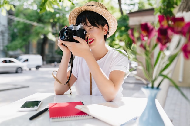 Elegante mujer joven con pelo corto oscuro haciendo fotografía profesional