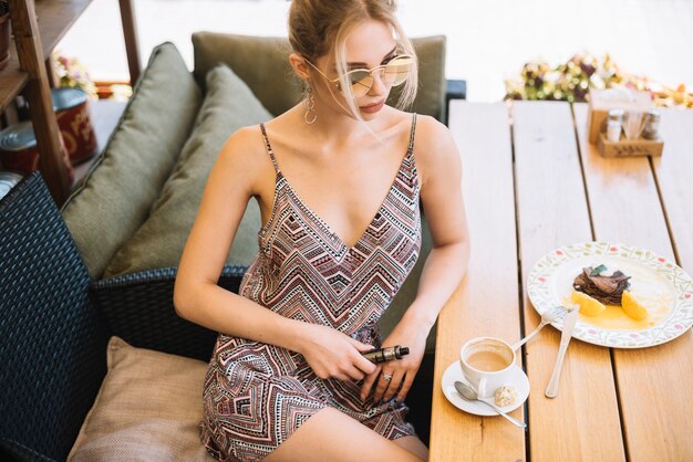 Elegante mujer joven sentada en el café con café y desayuno