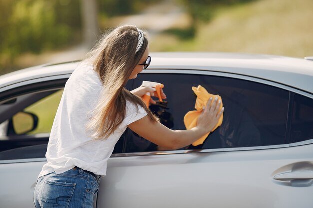 Elegante mujer limpia el auto con un trapo