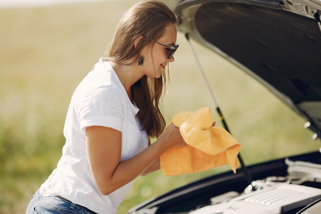 Elegante mujer limpia el auto con un trapo