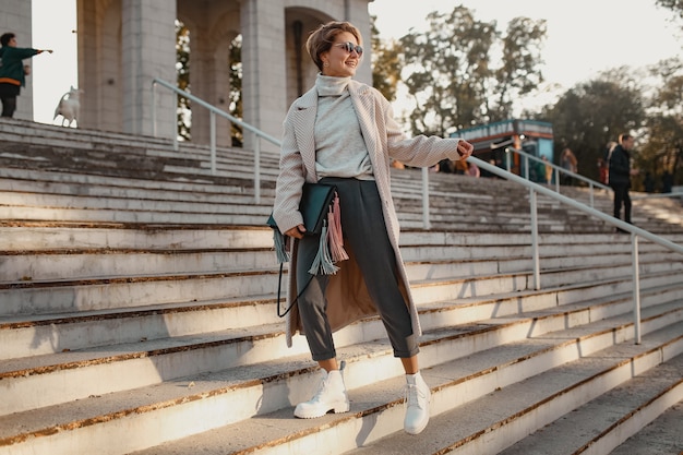 Elegante mujer de moda segura caminando en la calle con abrigo de estilo elegante