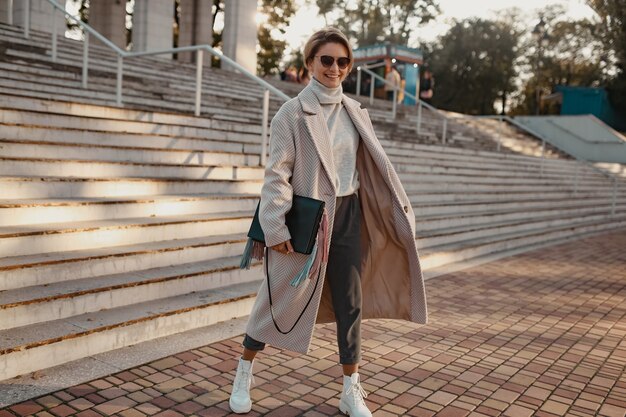 Elegante mujer de moda segura caminando en la calle con abrigo de estilo elegante